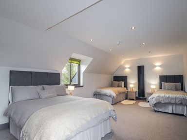 A bedroom with three beds two bedside tables lamps and a window at Ben Luna Lodge in Drumnadrochit Loch Ness