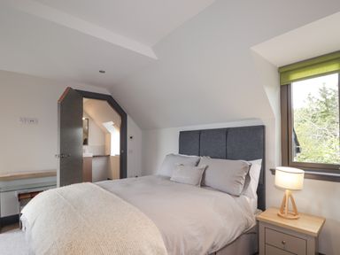 A bedroom with a bed lamp window and open door to a bathroom at Ben Luna Lodge in Drumnadrochit Loch Ness