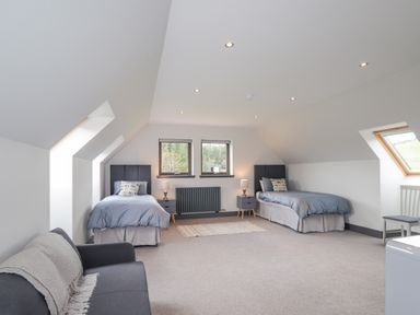 A bedroom with two single beds and a sofa at Ben Luna Lodge in Drumnadrochit Loch Ness