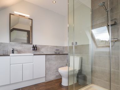 A bathroom with a sink and mirror a toilet and a glass shower enclosure at Ben Luna Lodge in Drumnadrochit Loch Ness