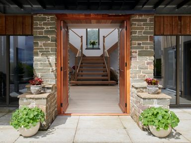 An entrance with open wooden doors stone walls potted plants and stairs inside at Ben Luna Lodge in Drumnadrochit Loch Ness