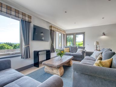 A living room with sofas a wooden coffee table a TV and large windows at Ben Luna Lodge in Drumnadrochit Loch Ness