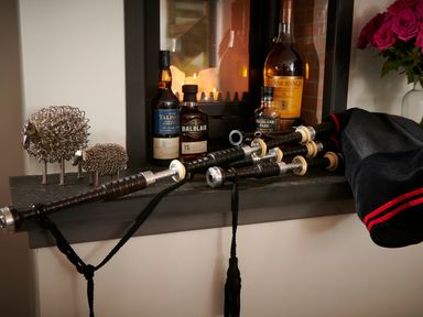 A shelf with bagpipes bottles of whisky decorative metal sheep and flowers at Ben Luna Lodge in Drumnadrochit Loch Ness