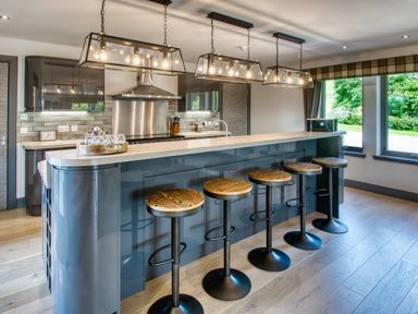 A kitchen with a long island and five bar stools under hanging lights at Ben Luna Lodge in Drumnadrochit Loch Ness