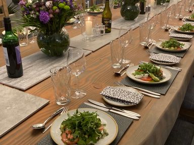 A dining table set with plates of salad wine bottles glasses and a vase with flowers at Ben Luna Lodge Drumnadrochit Loch Ness