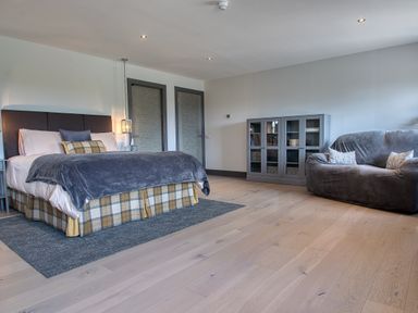 A bedroom with a bed a gray cabinet and a gray armchair at Ben Luna Lodge in Drumnadrochit Loch Ness