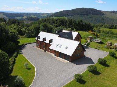 A house with a white roof and wooden walls surrounded by grass and trees at Ben Luna Lodge in Drumnadrochit Loch Ness