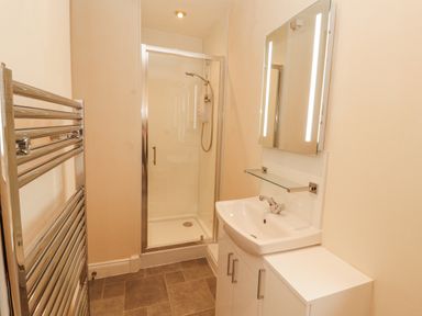 A bathroom with a shower, sink, and mirror at Flat 17 in Keswick