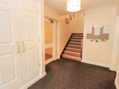 A hallway with a staircase and a wardrobe at Flat 17 in Keswick