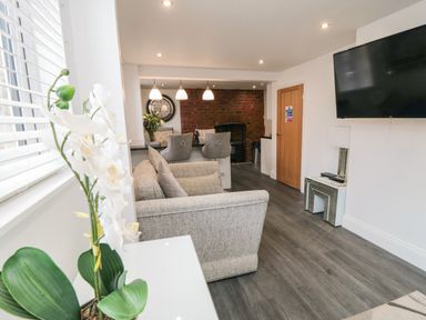A living room with a couch a mounted television and a dining area with chairs at Tower Apartment in Whitby