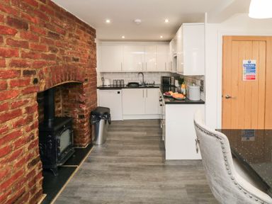 A kitchen with white cabinets a black countertop and a brick fireplace with a stove at Tower Apartment in Whitby