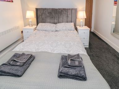 A bedroom with a bed towels nightstands lamps and a mirror at Tower Apartment in Whitby