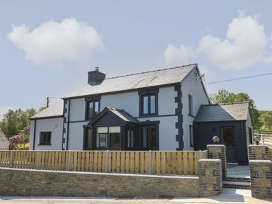 A two story house with black and white exterior and a wooden fence in front at Rhiwmynach in Pontarfynach near Aberystwyth