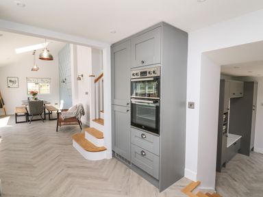 A kitchen with built-in ovens a dining table with chairs and benches and a stairway at Rhiwmynach in Pontarfynach near Aberystwyth