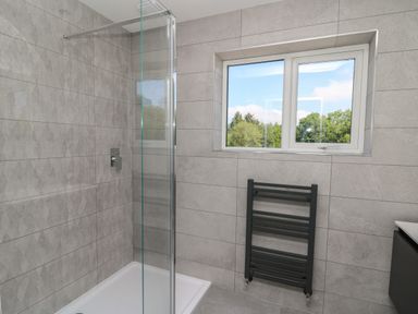 A bathroom with a walk-in shower glass panel window and a heated towel rail at Rhiwmynach in Pontarfynach near Aberystwyth