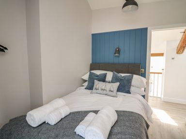 A bedroom with a bed with pillows and rolled towels at Rhiwmynach in Pontarfynach near Aberystwyth