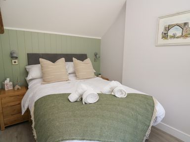 A bedroom with a bed made with white linens green throw and beige pillows at Rhiwmynach Pontarfynach near Aberystwyth