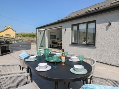 An outdoor dining table set with plates glasses and a bottle on a patio outside a house at Rhiwmynach Pontarfynach near Aberystwyth