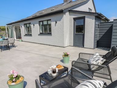 An outdoor patio area with chairs pillows small table coffee and pastries and potted flowers at Rhiwmynach in Pontarfynach near Aberystwyth
