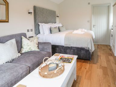 A bedroom with a double bed and a grey sofa with cushions at The Folly in Linton near Thresfield