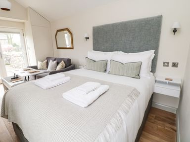 A bedroom with a bed and folded towels a sofa and a mirror on the wall at The Folly in Linton near Thresfield