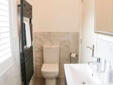 A bathroom with a toilet sink a towel rail and a window with blinds at The Folly in Linton near Thresfield