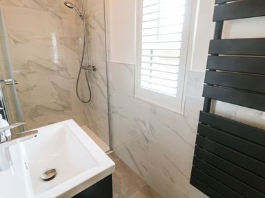 A bathroom with a sink shower area window with blinds and black heated towel rail at The Folly in Linton near Thresfield