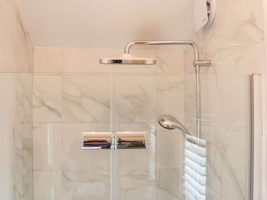 A shower area with a rainfall showerhead glass partition and marble tiled walls at The Folly in Linton near Thresfield