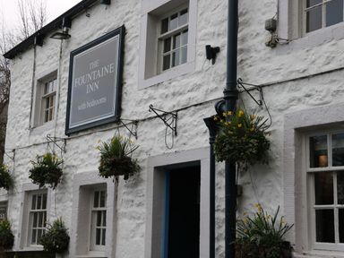 The exterior wall of The Fountaine Inn with hanging flower baskets and windows in Linton near Thresfield