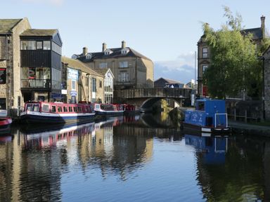 A canal with narrowboats docked along the side and a stone bridge in the background at The Folly in Linton near Thresfield