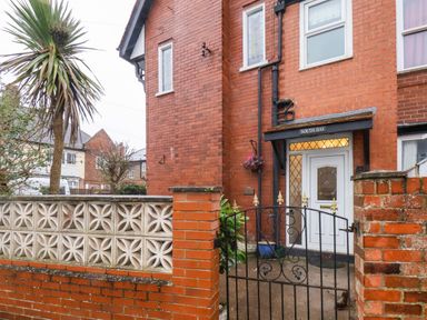 The entrance to a brick house with a white door and metal gate at South Bay Beach House in Bridlington