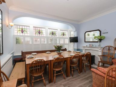 A dining room with wooden table and chairs stained glass windows and a wall mounted TV at South Bay Beach House in Bridlington