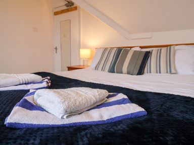 A bedroom with a bed covered with white and blue towels and striped cushions on the bed at South Bay Beach House Bridlington