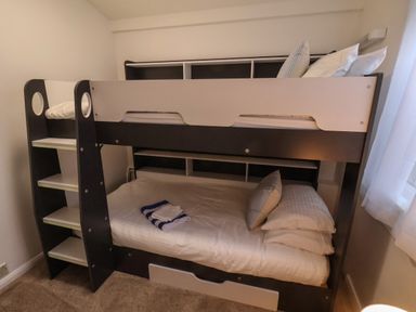 A bunk bed with pillows and folded towels in a bedroom with a window at South Bay Beach House in Bridlington