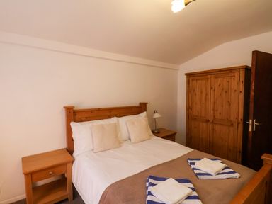 A bedroom with a double bed two bedside tables a table lamp and a wooden wardrobe at South Bay Beach House in Bridlington