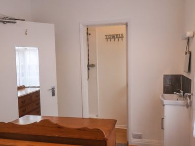 A bedroom doorway leading to a bathroom with a towel rack and a wooden dresser reflected in a mirror on the door at South Bay Beach House in Bridlington