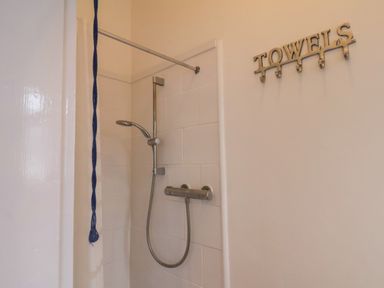 A shower area with a handheld showerhead and a TOWELS hook on the wall at South Bay Beach House in Bridlington