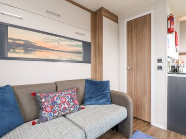 A living area with a sofa and cushions next to a wooden door at Balvicar Beag Balvicar Isle Of Seil