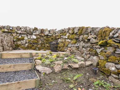 A small garden area with stone steps plants and mossy stone walls at Balvicar Beag in Balvicar Isle Of Seil