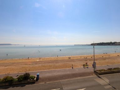 A beach with people walking and a pier at 123 On The Sea – Victoria’s Place in Weymouth