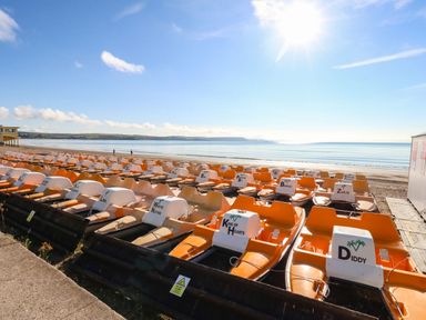 A row of pedal boats on the beach at 123 On The Sea – Victoria’s Place in Weymouth