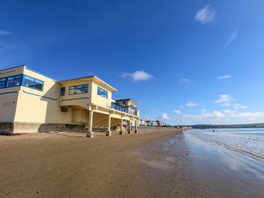 A beach with a building along the shore at 123 On The Sea – Victoria’s Place in Weymouth