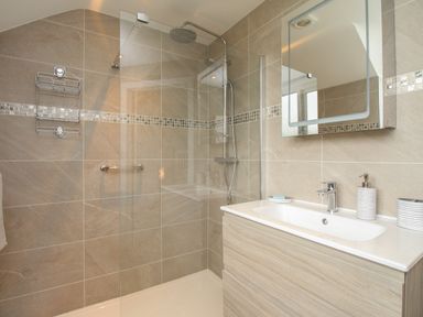 A bathroom with a walk in shower and a sink with a mirror above at Blue Waters in Weymouth