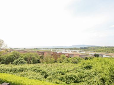 A view of houses with greenery and water beyond at Blue Waters in Weymouth