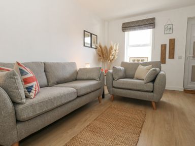 A living room with two grey sofas a window and wall art at The Nightingale in Weymouth