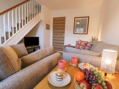 A living room with two sofas a wooden table with fruit and snacks and a lamp at The Nightingale in Weymouth