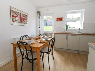 A kitchen with a wooden dining table set for four and a countertop with a sink at The Nightingale in Weymouth