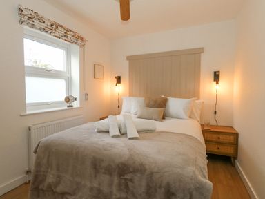 A bedroom with a double bed beige bedding bedside tables with lamps and a window at The Nightingale in Weymouth