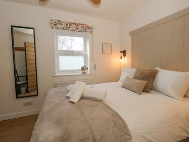 A bedroom with a bed towels a window and a wall mirror at The Nightingale in Weymouth