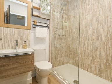 A bathroom with a toilet sink mirror towel rack and shower at The Nightingale in Weymouth